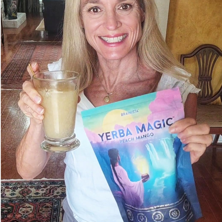 Smiling woman holding a glass of Yerba Magic drink and the product pouch