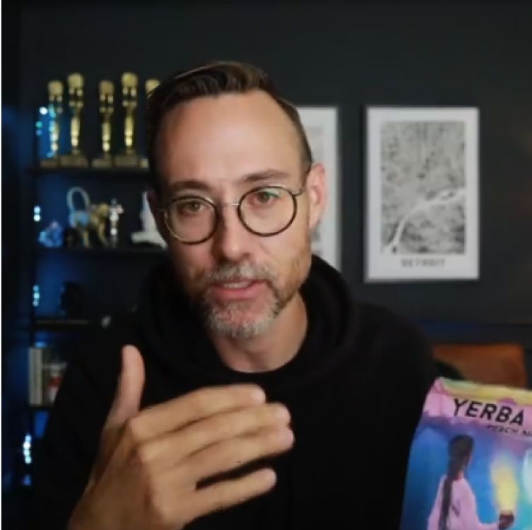 Man with glasses in a modern home office giving a thumbs up while holding a Yerba Magic pouch.