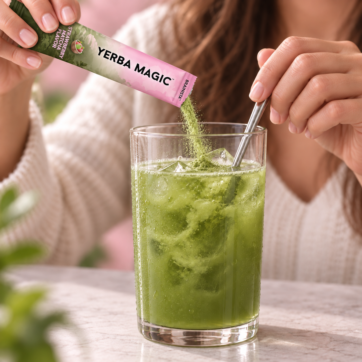 Pouring green Strawberry Matcha powder from an opened stick into water and stirring with a spoon